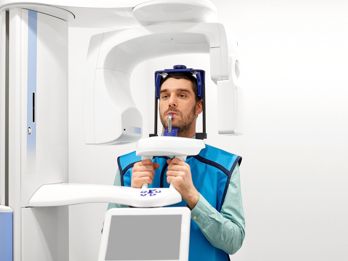 Male patient undergoing a panoramic dental X-ray scan with modern imaging equipment