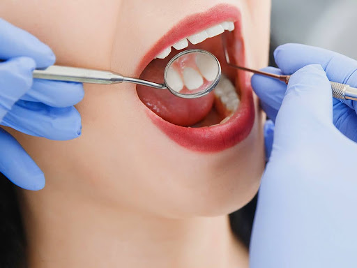 Close-up of a dental exam with mirror and probe inspecting a patient’s teeth