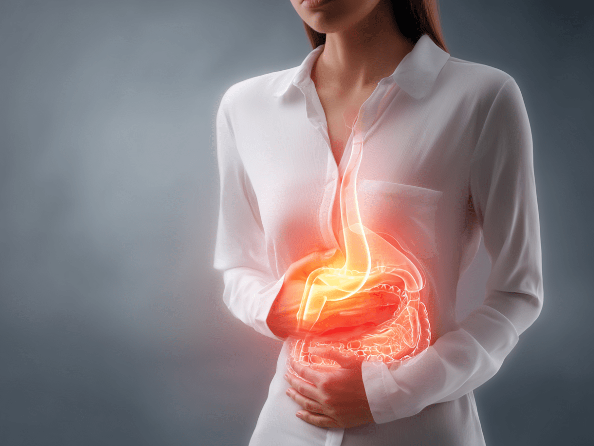 Woman in white shirt clutching abdomen with glowing illustration of stomach and esophagus, symbolizing acid reflux and its impact on dental enamel