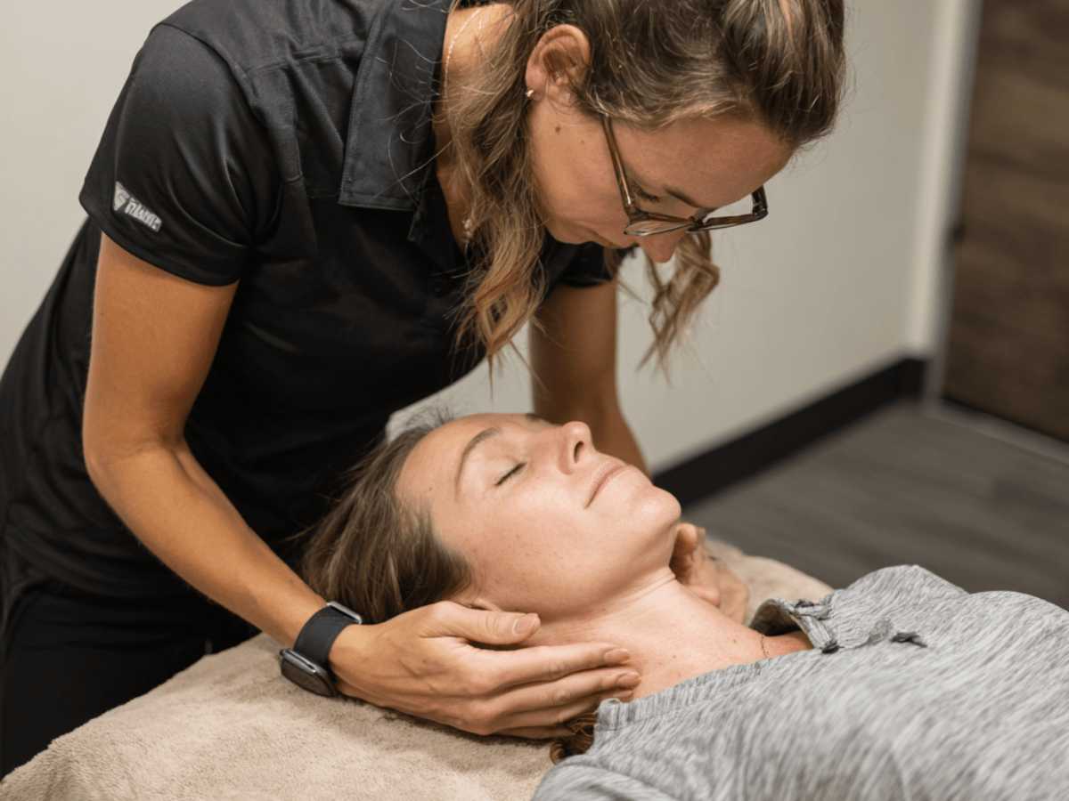Therapist applying hands-on myofunctional therapy techniques to a female patient’s jaw and neck muscles to improve alignment and alleviate TMJ-related discomfort
