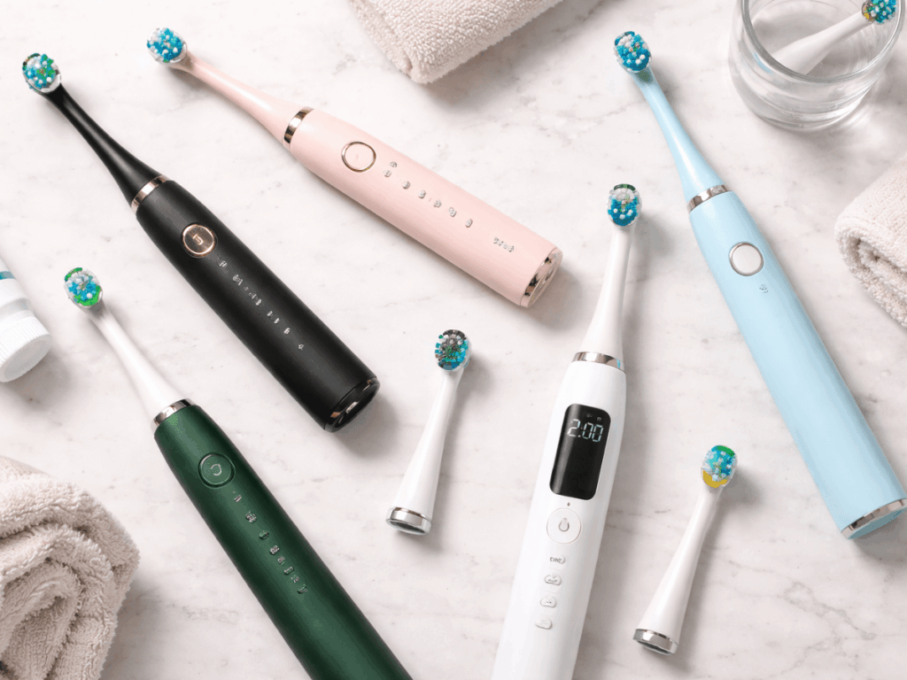 Flat lay of multiple electric toothbrushes with interchangeable brush heads, used for daily oral hygiene and plaque removal