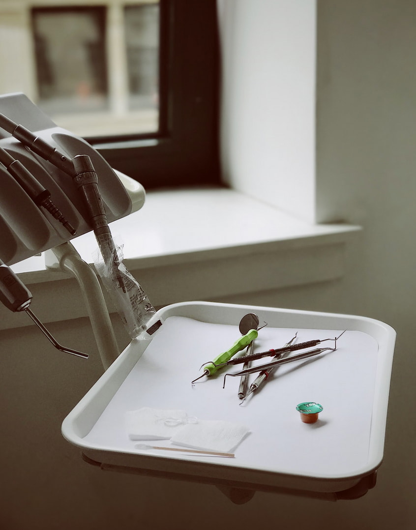 A tray containing a pair of scissors, a pair of tweezers, and another pair of tweezers arranged neatly. 