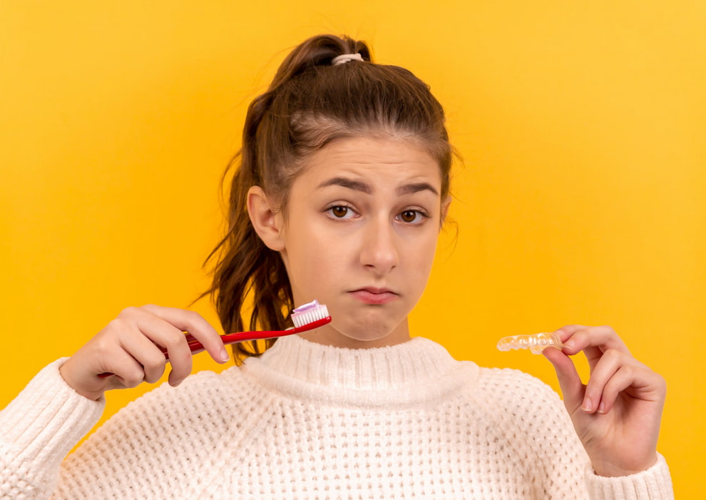 A woman examines a toothbrush she is holding, appearing thoughtful about its use.