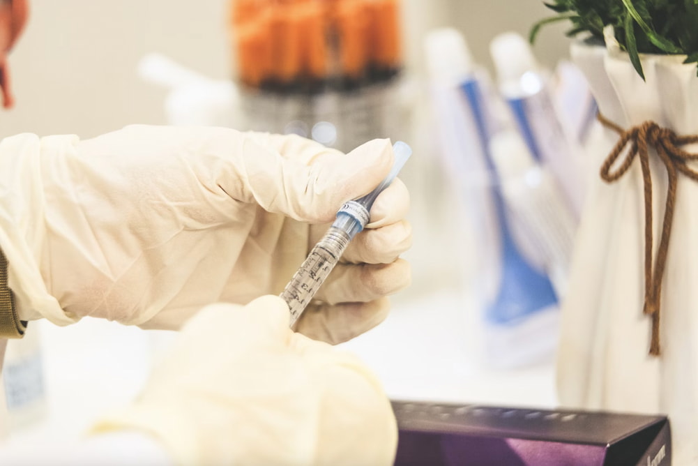 A lab-coated individual is holding a syringe, indicating readiness for a medical task or injection.