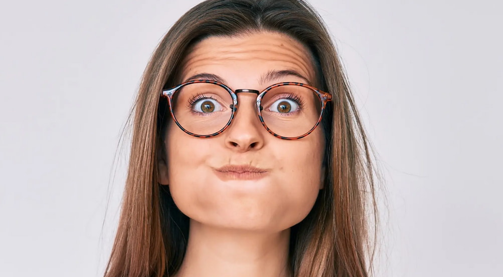 A woman wearing glasses, looking directly at the camera with a neutral expression.