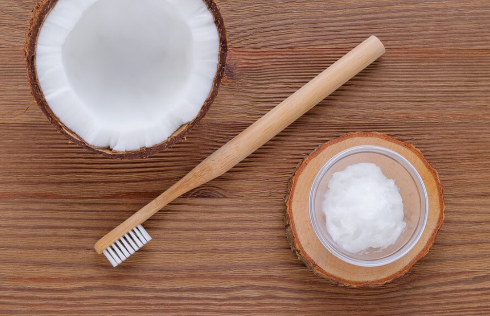 Coconut toothpaste and a toothbrush placed on a wooden table, showcasing a natural oral care routine. 
