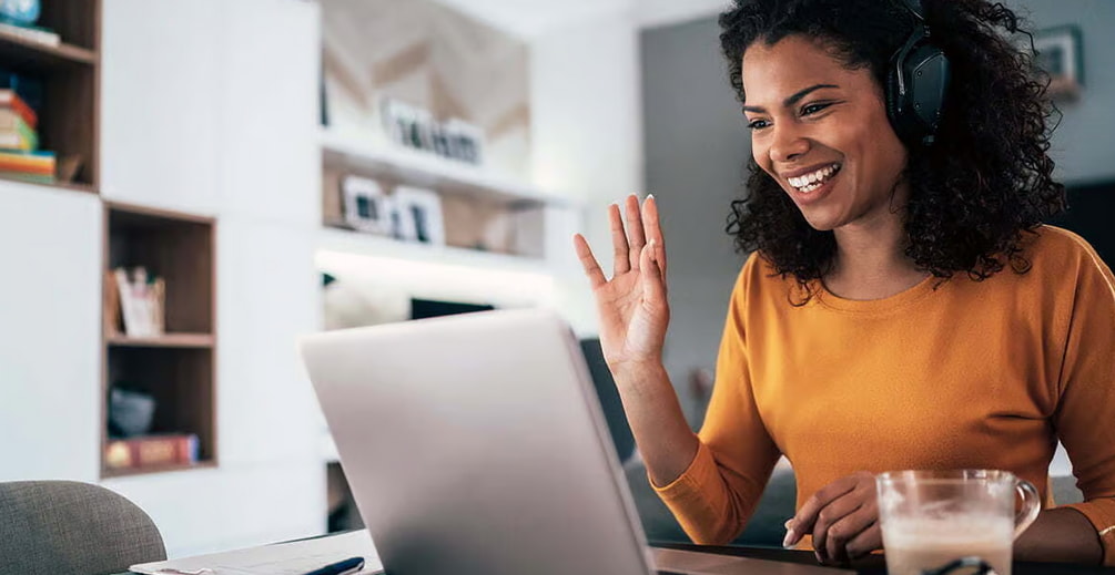 A woman with headphones sits at a desk, focused on her laptop while working or studying. 