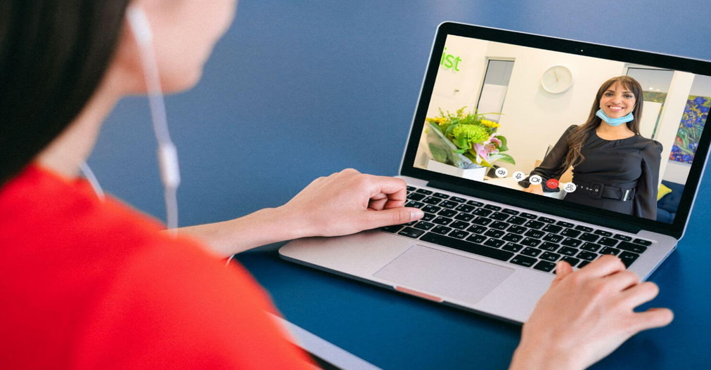 A woman video chatting with a doctor on her laptop, engaged in a virtual consultation.