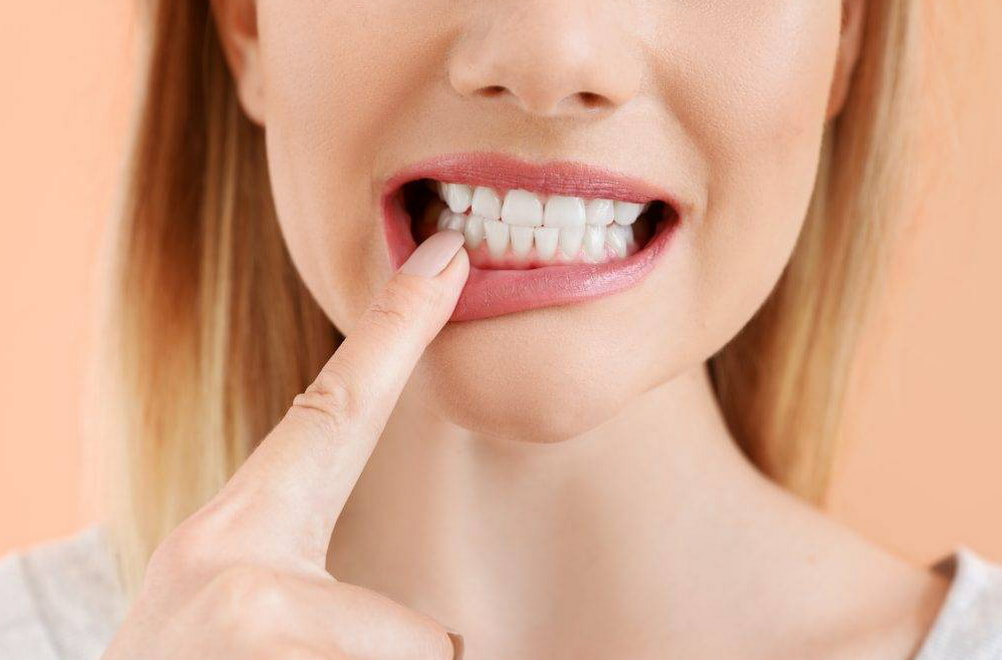 A woman holds her finger to her teeth, appearing thoughtful or contemplative. 