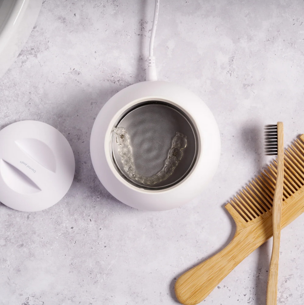 A toothbrush, a tube of toothpaste, and a toothbrush holder arranged neatly on a bathroom countertop. 