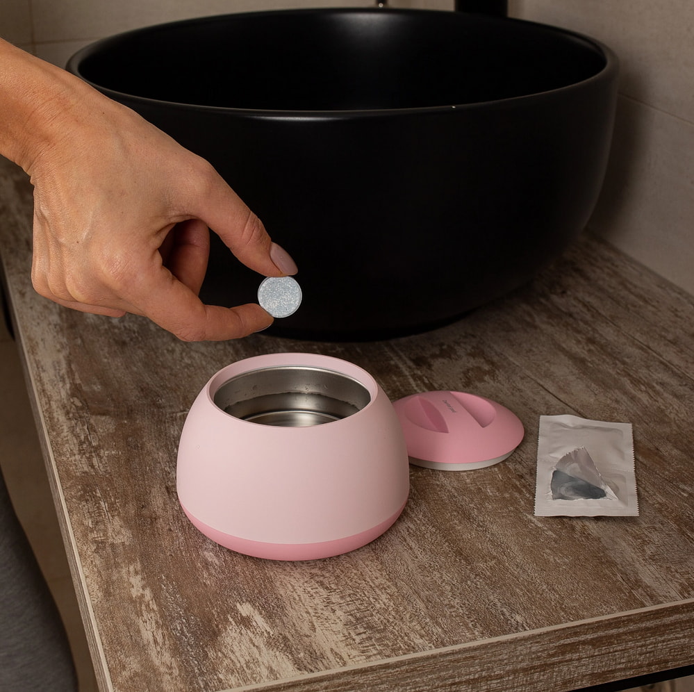 A hand inserting a pink container into a black bowl, showcasing a simple kitchen activity.
