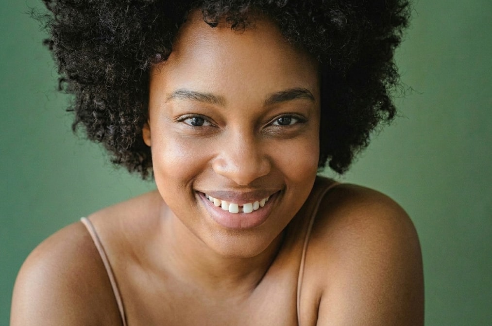 A woman with curly hair smiles warmly, showcasing her joyful expression. 
